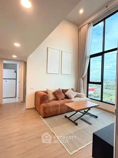 Modern living room with large windows and city view, featuring stylish furniture and decor.