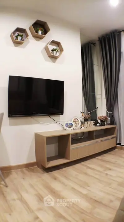 Modern living room with wall-mounted TV and stylish decor in a cozy apartment.