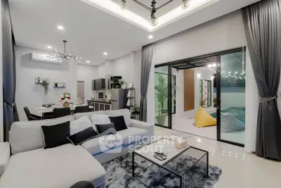 Luxurious modern living room with open kitchen and pool view, featuring elegant decor and spacious layout.