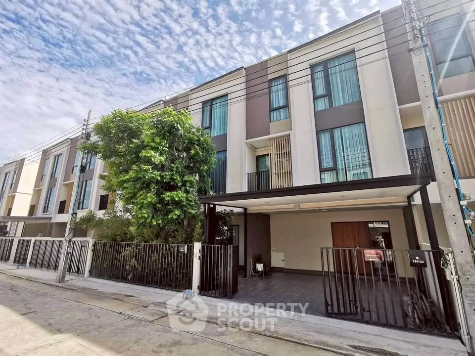 Modern townhouse exterior with sleek design and spacious driveway under a clear blue sky.
