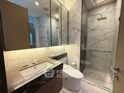 Luxurious modern bathroom with marble finishes and glass shower enclosure.
