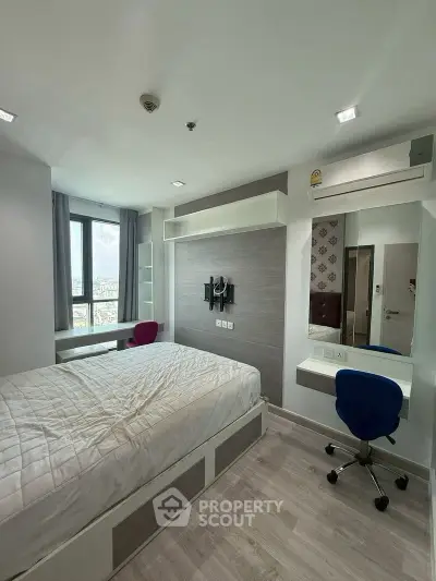 Modern bedroom with stylish decor and large window offering city views, featuring a comfortable bed and workspace.
