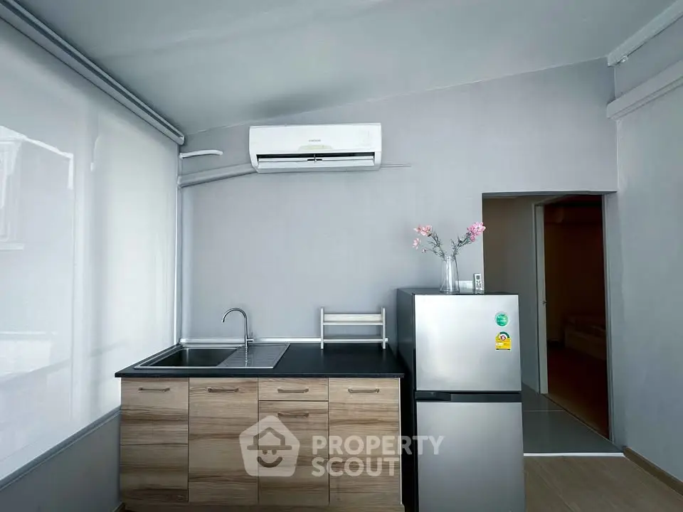 Modern kitchen with sleek cabinetry and compact fridge in minimalist apartment.