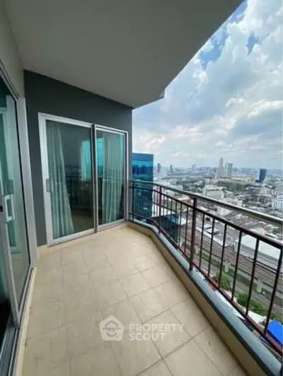 Spacious balcony with stunning cityscape views in modern high-rise apartment.