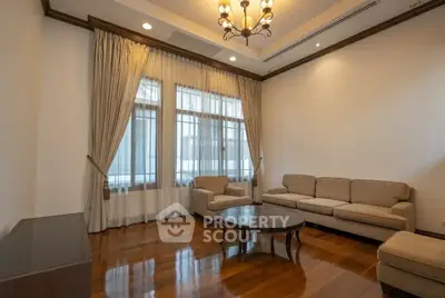 Elegant living room with hardwood floors, plush sofas, and large windows with drapes.