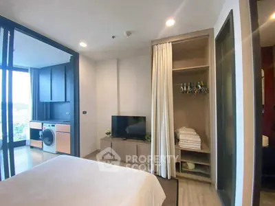 Modern bedroom with open closet and in-unit laundry, featuring a sleek design and city view.