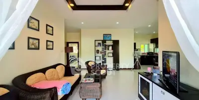 Spacious living room with cozy seating and modern decor, open layout to kitchen area.