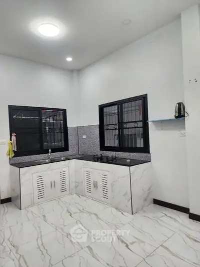 Modern kitchen with sleek countertops and tiled flooring, featuring a minimalist design and ample natural light.