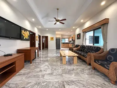 Spacious living room with modern decor and open layout, featuring marble flooring and ceiling fan.