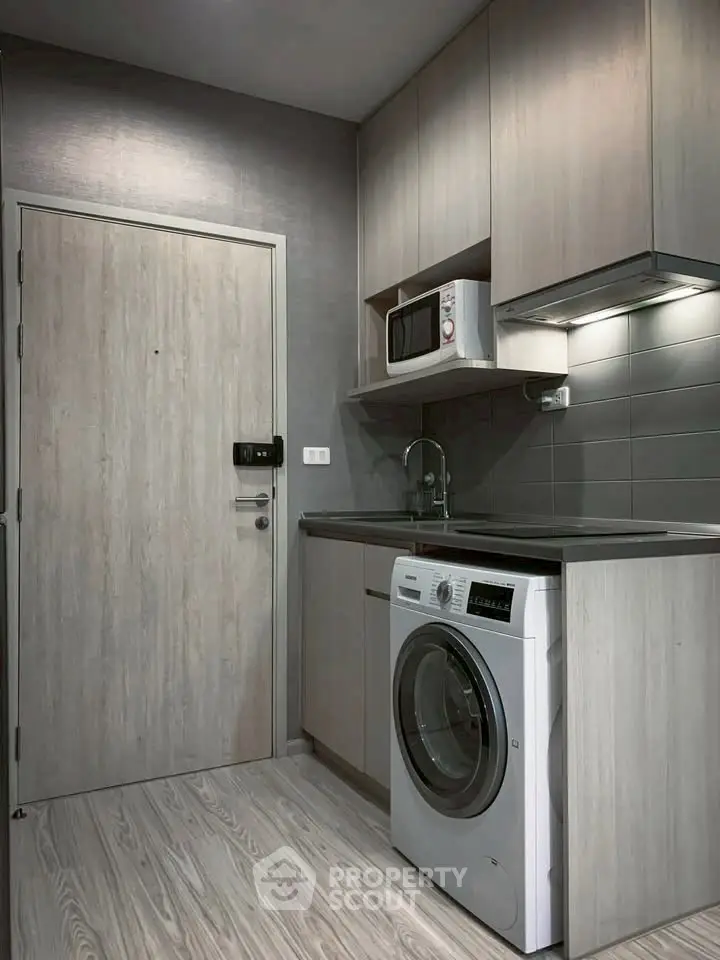 Modern compact kitchen with washing machine and microwave in sleek design.