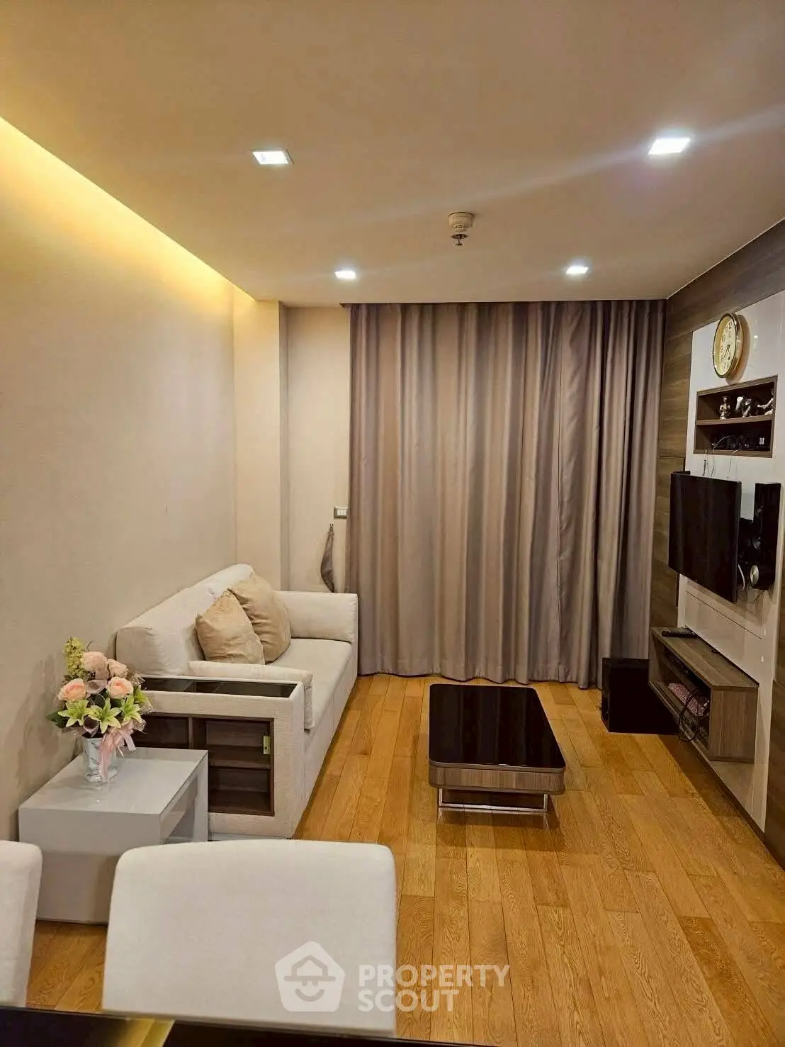 Modern living room with cozy sofa, wooden flooring, and wall-mounted TV for stylish comfort.