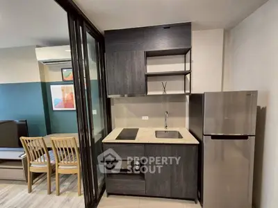 Modern compact kitchen with sleek cabinetry and stainless steel appliances in stylish apartment.