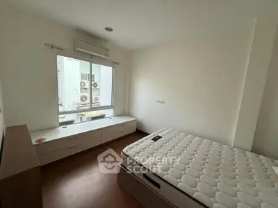 Spacious bedroom with large window and modern furnishings in a bright apartment.