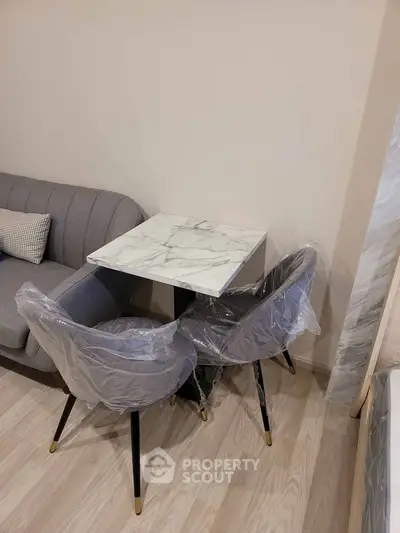 Modern living room with stylish marble table and elegant gray chairs, perfect for cozy gatherings.