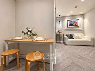 Modern living room with stylish decor and cozy dining area, featuring elegant wooden flooring and contemporary artwork.