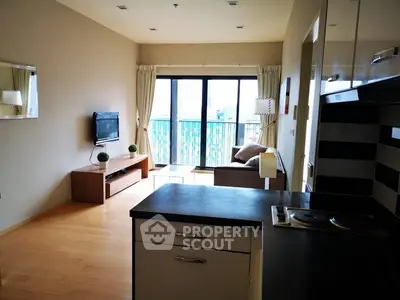 Modern living room with open kitchen and balcony view, featuring sleek design and natural light.