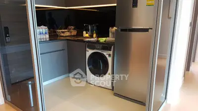 Modern kitchen with sleek appliances and integrated washing machine in stylish apartment.