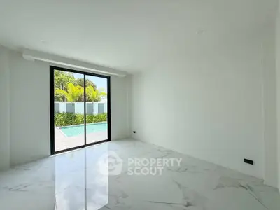 Spacious modern room with marble flooring and large glass doors opening to a lush garden view.