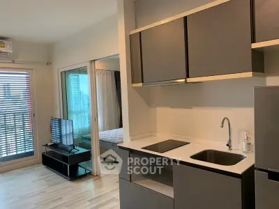 Modern apartment interior with sleek kitchen and cozy living area, featuring large windows and city view.