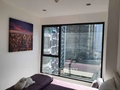 Cozy bedroom with large window offering stunning cityscape views in modern high-rise apartment.