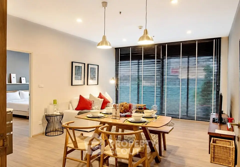 Modern living room with dining area, stylish furniture, and large windows with blinds.