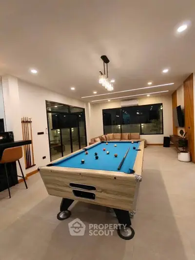 Modern living room with pool table and stylish lighting, perfect for entertainment and relaxation.