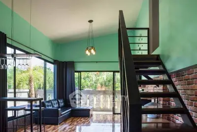 Spacious living room with modern staircase and large windows offering lush garden views.