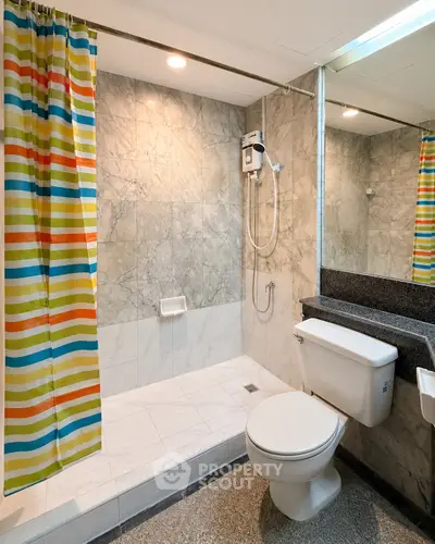 Modern bathroom with marble tiles and colorful shower curtain