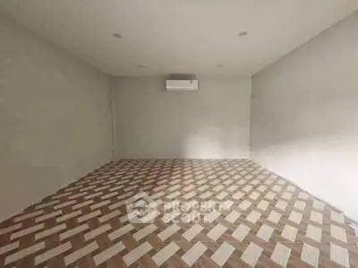Spacious empty room with unique patterned flooring and air conditioning unit.