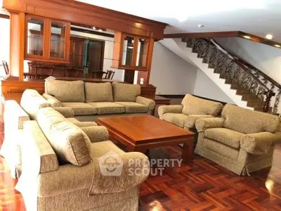 Spacious living room with elegant wooden furniture and staircase, perfect for family gatherings.