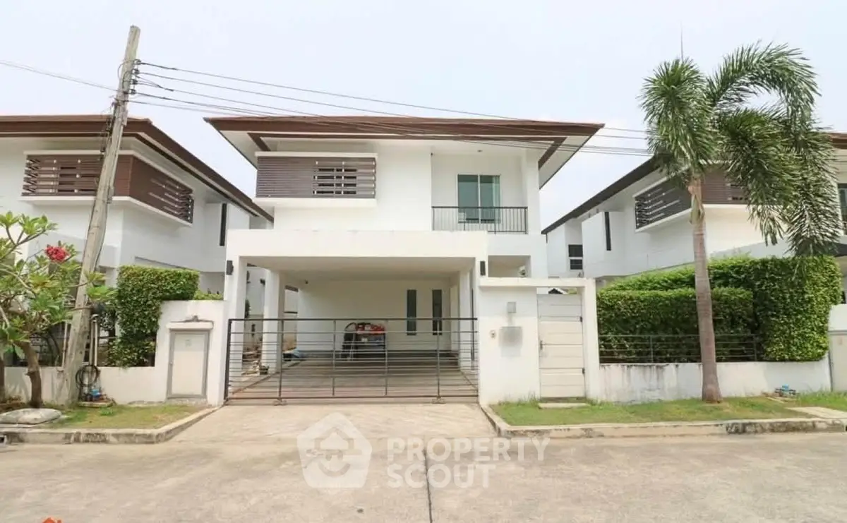 Modern two-story house with a sleek design, featuring a spacious driveway and lush greenery.