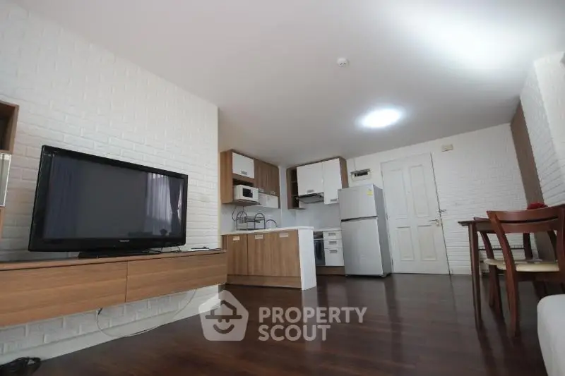 Modern living room with open kitchen, wooden flooring, and sleek furniture design.