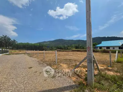 Scenic land plot with mountain views, ideal for development or investment, featuring clear skies and lush surroundings.
