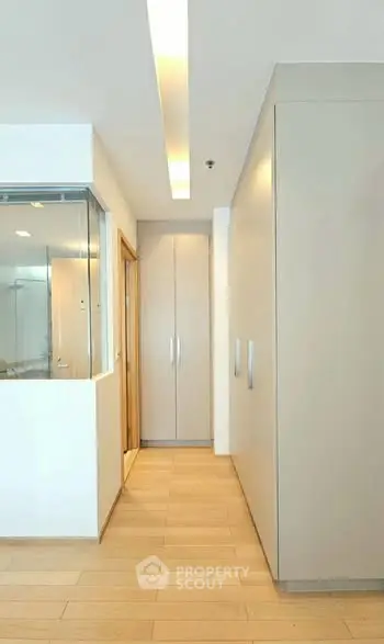 Modern hallway with sleek storage and wooden flooring in a contemporary apartment.