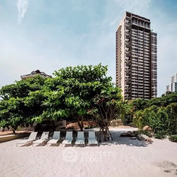 Luxurious beachfront property with tall modern building and lush greenery