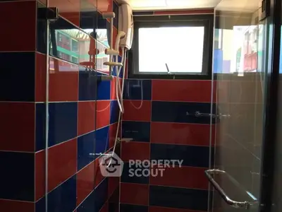 Vibrant bathroom with red and blue tiles and modern shower fixtures.