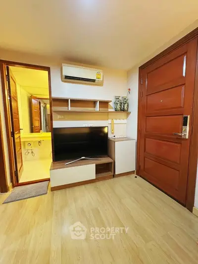 Cozy living room with wooden flooring, modern TV stand, and air conditioning unit.