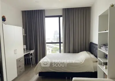 Spacious bedroom with modern furnishings and large window offering city views.