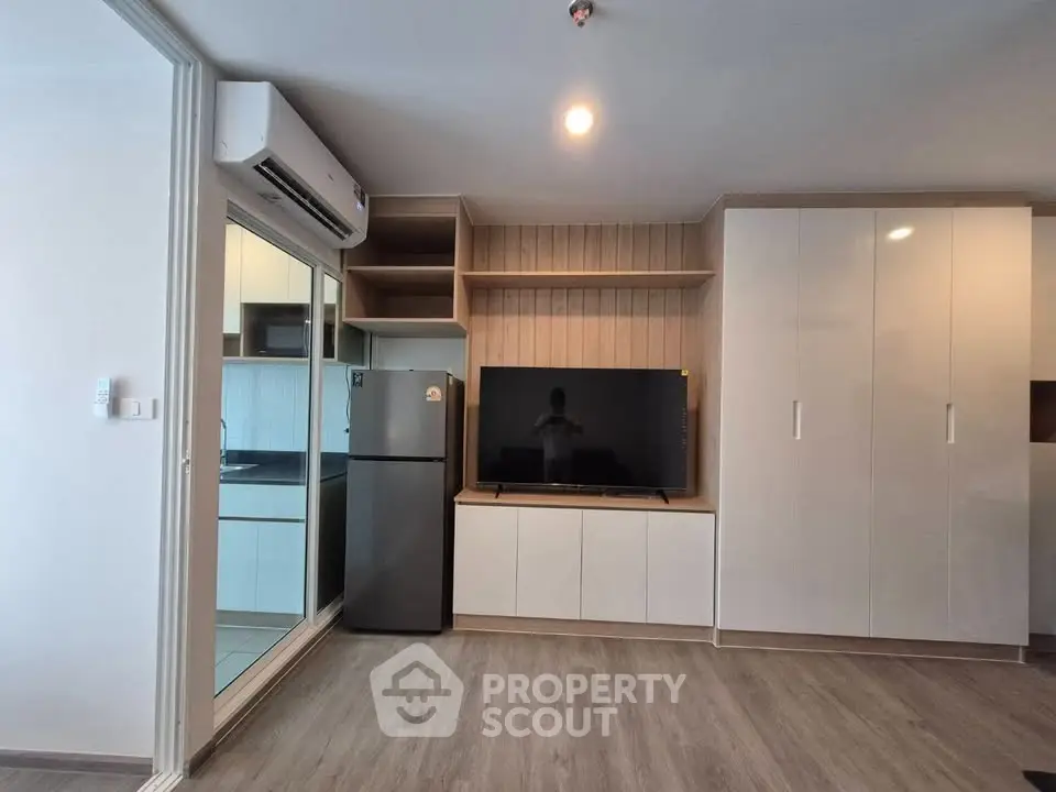 Modern living room with sleek cabinetry and integrated kitchen appliances in a stylish apartment.