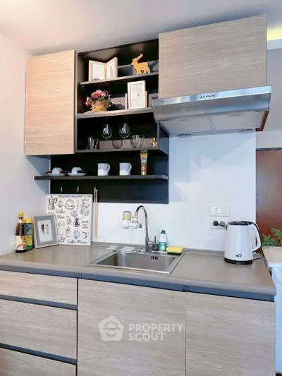 Modern kitchen with sleek cabinetry and stainless steel sink, featuring open shelving and stylish decor.