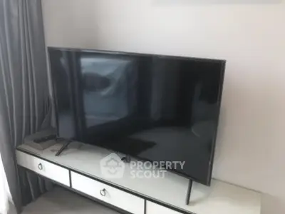 Modern living room with sleek flat-screen TV and elegant curtains, perfect for entertainment.