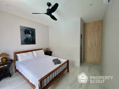 Spacious bedroom with polished marble flooring, modern wooden furniture, and a sleek ceiling fan, offering a serene and comfortable living space.