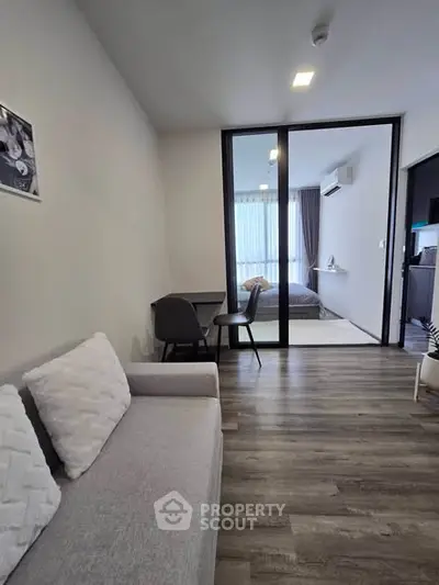 Modern apartment interior with open layout, featuring a cozy living area and a view into the bedroom.
