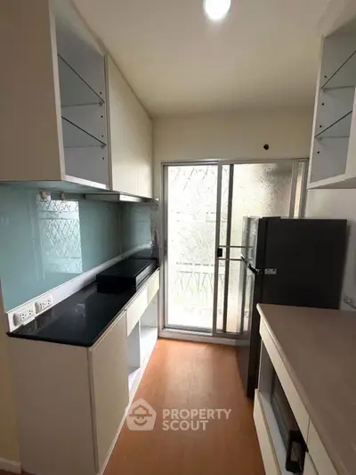 Modern kitchen with sleek cabinetry and large window for natural light.