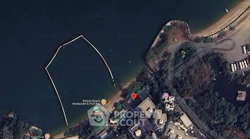 Aerial view of waterfront property near a beach with lush surroundings.
