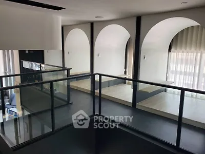 Modern interior with arched windows and sleek glass railing, perfect for contemporary living.