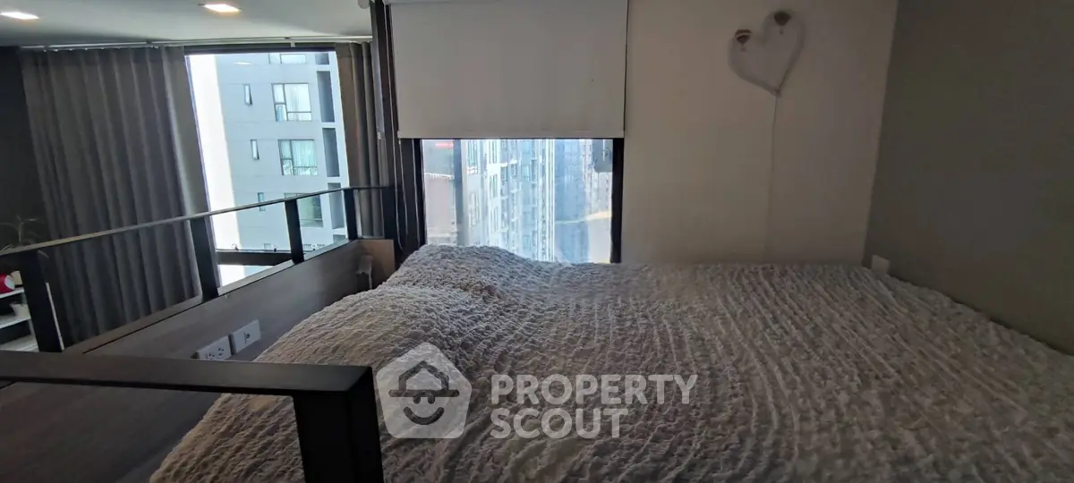 Cozy bedroom with large window offering city view in modern apartment