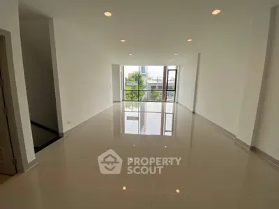 Spacious modern living room with glossy tiled floors and large windows offering natural light.