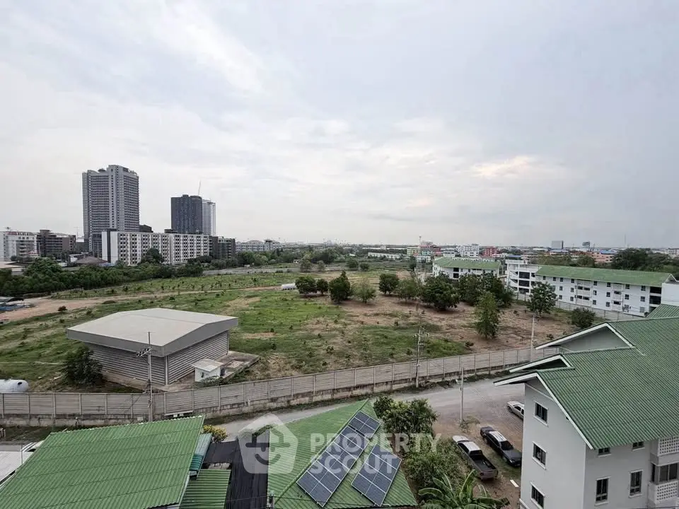 Expansive cityscape view from a high-rise building showcasing urban development and green rooftops.