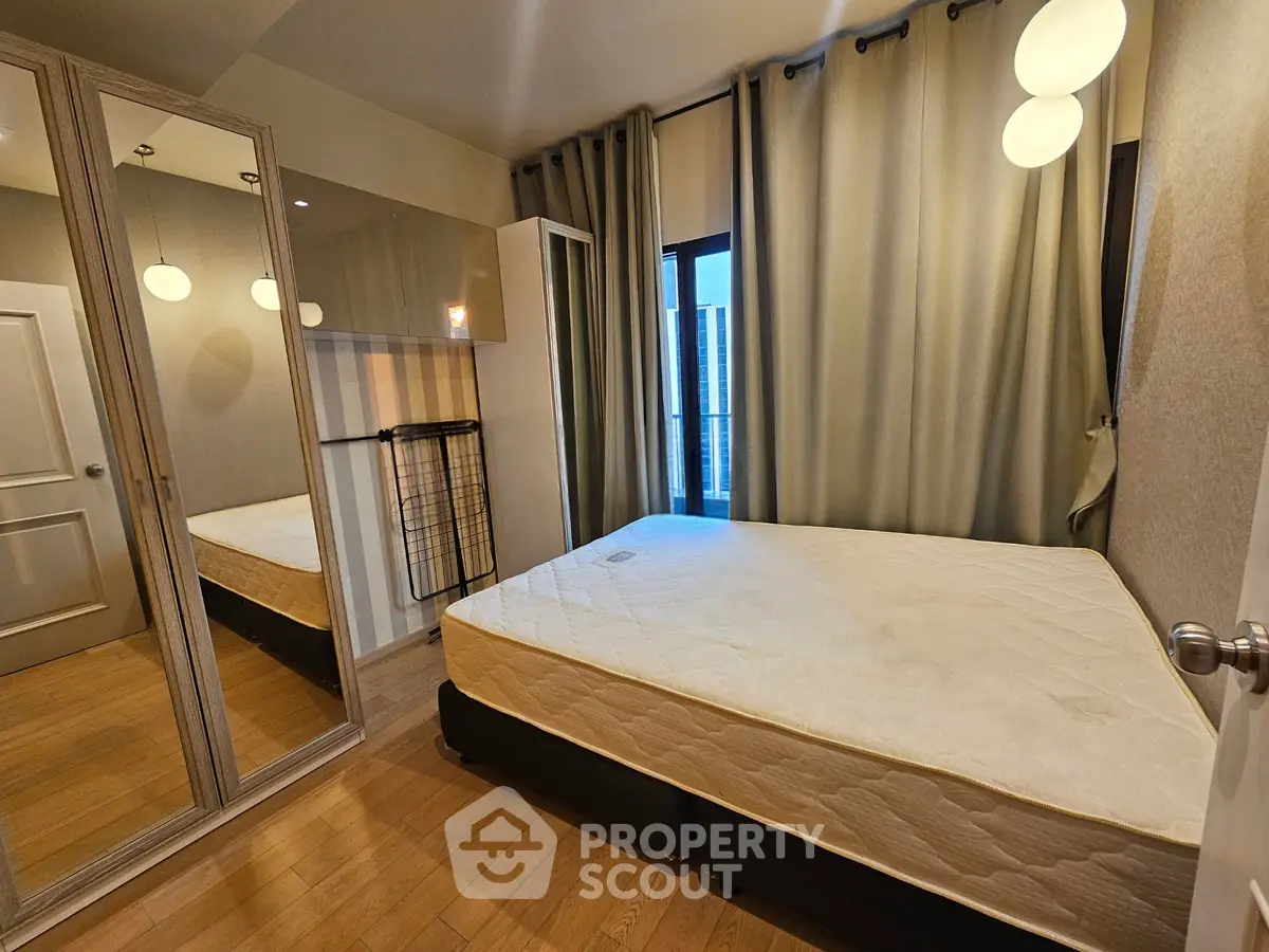 Cozy bedroom with large mirror and modern lighting in urban apartment